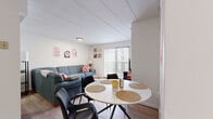 Located at 224 S Burrowes St in State College, PA, this two-bedroom, two-bathroom unit offers a practical and well-organized single-floor layout. The open living and dining area is bright and welcoming, featuring wood-style flooring, white walls, and a large sliding glass door with vertical blinds that opens to a balcony and fills the space with natural light. The dining area comfortably accommodates a round table with seating for four, flowing seamlessly into the living room. The galley-style kitchen is outfitted with warm wood cabinetry, granite-style countertops, a dark tile backsplash, and white appliances including a range, dishwasher, refrigerator, and microwave, all set against tile flooring and a bold accent wall. Both bedrooms are carpeted and include closet storage — the primary bedroom features sliding wood closet doors and connects to its own bathroom. Each bathroom includes a tub-shower combination; one is finished with white tile and a sliding glass door, and the other with classic tile flooring and a curtained tub. A hallway connects the rooms efficiently, with four closets distributed throughout the unit providing ample storage throughout the home.