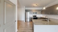 Located at 1332 Holly Rush Ln in Denver, NC, this single-floor residence showcases a clean, contemporary design with consistent, high-quality finishes throughout. The open-concept kitchen is a standout feature, equipped with stainless steel appliances, sleek gray cabinetry, a white subway tile backsplash, and a granite-topped island with a built-in sink and pendant lighting overhead — ideal for both cooking and casual dining. Light wood-style flooring flows throughout the main living areas, lending warmth and continuity to the space. The living area is bright and airy, enhanced by a ceiling fan and access to natural light through large windows with views of the surrounding landscape. Bedrooms are carpeted for comfort and feature windows that bring in ample natural light and outdoor views. The primary bathroom is well-appointed with a dual-sink granite vanity, gray cabinetry, and a glass-enclosed shower. A secondary bathroom features a clean, fully tiled soaking tub and shower combination with chrome fixtures. A dedicated laundry area with full-size washer and dryer hookups adds everyday convenience. Throughout the home, sage-toned panel doors, chrome hardware, and crisp white walls create a cohesive, modern aesthetic.