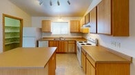 Located at 1770 Dublin Trail in Neenah, Wisconsin, this single-floor unit offers a practical and well-organized layout designed for comfortable everyday living. The kitchen is a functional centerpiece, featuring warm wood-tone cabinetry, ample counter space, a central island, tile flooring, and white appliances including a range, dishwasher, and refrigerator. Track lighting illuminates the space, and a window above the sink brings in natural light with views of the surrounding greenery.

The bedrooms are carpeted and finished with neutral tones, warm wood baseboard trim, and ceiling fans for year-round comfort. Each room includes baseboard heating and windows that allow natural light in while offering outdoor views. Closet space is accessible directly from the bedroom areas, providing convenient storage.

A dedicated laundry area accommodates a full-size washer and dryer, adding in-unit convenience. Additional built-in shelving provides organized storage nearby. The bathroom includes a full tub-shower combination with tile flooring and clean, neutral finishes throughout.

The overall layout, visible in the floorplan view, is open and efficiently organized, connecting the kitchen, living areas, and private rooms in a cohesive flow. Vaulted ceilings in select areas add a sense of openness to the space.