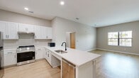 Located at 5790 Stockport St in Riverview, FL, this well-appointed one-bedroom, one-bathroom unit offers a thoughtfully designed single-floor layout. Light wood-style flooring flows seamlessly throughout the entire space, complemented by neutral warm-gray walls and crisp white trim, creating a clean and modern aesthetic.

The open-concept kitchen and living area serves as the heart of the unit. The kitchen features white shaker-style cabinetry, stainless steel appliances including a gas range and refrigerator, recessed lighting, and a large island with a white quartz countertop and undermount sink with a matte black faucet — ideal for both cooking and casual dining. The adjacent living area is bright and open, with a window allowing natural light to fill the space.

The bedroom is a comfortable, well-sized room equipped with a ceiling fan, a built-in closet, and a window with outdoor views. A hallway connects the main living areas to the bedroom and bathroom.

The bathroom is designed with accessibility in mind, featuring a wall-mounted vanity with an open base, a large mirror with overhead lighting, matte black fixtures, and wood-style flooring consistent with the rest of the unit. The overall ambiance is modern, clean, and move-in ready.
