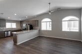 This single-story home in Hesperia, California offers a well-designed, open-concept layout that seamlessly connects the kitchen, dining, and living areas. The great room features vaulted ceilings with a ceiling fan, arched windows that invite abundant natural light, and durable wood-look flooring throughout the main living spaces. The spacious kitchen is a standout, equipped with rich dark-toned cabinetry, granite countertops, a large center island, and a full suite of stainless steel appliances including a refrigerator, gas range, microwave, and dishwasher. Recessed lighting and arched window accents add to the kitchen's polished aesthetic. The bedrooms are carpeted for comfort, with the primary suite boasting high ceilings, a ceiling fan, a walk-in closet, and an en-suite bathroom featuring granite countertops, dark cabinetry, and a glass-enclosed walk-in shower. A secondary bathroom mirrors the same quality finishes and includes a tub-shower combination. Additional highlights include a spacious, attached two-car garage with an automatic opener and clean concrete flooring. The home's neutral color palette and consistent, quality finishes throughout create a cohesive and move-in-ready living environment.