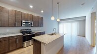 Located at 7944 Watts Rd in Madison, Wisconsin, this single-floor residence offers a thoughtfully designed open-concept layout that seamlessly connects the kitchen and living areas. The kitchen serves as the centerpiece of the space, showcasing rich dark-espresso cabinetry with sleek hardware, granite countertops, and a full suite of stainless steel appliances including a range, microwave, and refrigerator. A central island with an integrated sink and pendant lighting overhead adds both functionality and visual appeal. Light-toned hardwood flooring runs throughout the main living area, enhancing the sense of openness and warmth. Large windows with vertical and horizontal blinds allow for generous natural light while offering privacy. The bedroom is a calm, neutral retreat featuring plush carpeting, vaulted ceiling detail, and a broad window that fills the room with daylight. The bathroom is finished with dark cabinetry paired with a crisp white countertop, a full tub-shower combination, and tile flooring. A ceiling fan is also present in the unit, contributing to comfort throughout the seasons. The overall design reflects a clean, contemporary aesthetic with consistent finishes and a practical, well-organized floor plan.