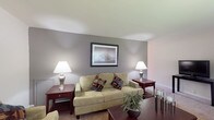 This single-floor residence offers a thoughtfully designed layout that balances comfort and functionality across its key living areas. The living room serves as the heart of the home, featuring neutral-toned walls with a warm gray accent wall, plush wall-to-wall carpeting, and ample space for multiple seating arrangements. Framed artwork adorns the walls, contributing to a calm and welcoming ambiance throughout.

The kitchen is bright and practical, finished with white cabinetry, light tile flooring, and a clean countertop workspace. A skylight adds natural light from above, while a sliding glass door opens directly onto a private outdoor balcony — ideal for enjoying fresh air and exterior views. A dedicated dining area adjacent to the kitchen provides a comfortable space for meals.

The bedroom is generously proportioned, offering soft carpeting, large windows that invite natural light, and a closet for ample storage. The room's neutral palette and understated design create a restful retreat.

The full bathroom is clean and efficiently laid out, featuring a tub-shower combination with white tile surround, a vanity with sink, and tile flooring. Throughout the residence, the consistent use of neutral tones and practical finishes creates a cohesive and livable environment.
