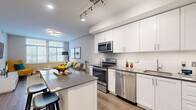 Located at 3400 South Clark Street in Arlington, VA, this well-appointed one-bedroom, one-bathroom residence offers a thoughtfully designed single-floor layout. The open-concept kitchen and dining area serves as the heart of the home, showcasing crisp white shaker cabinetry, a full suite of stainless steel appliances including a range, microwave, and dishwasher, a subway tile backsplash, and a granite-topped island with bar seating — ideal for casual dining and entertaining. Light wood-style flooring runs throughout the main living areas, adding warmth and continuity.

The living room is bright and welcoming, with large windows that invite generous natural light and provide views of the surrounding neighborhood. The bedroom, finished with plush carpeting, features a dedicated window and ample closet space — with four closets distributed throughout the unit providing excellent storage. The full bathroom includes a tiled tub-shower combination and a vanity with a dark stone countertop.

Additional practical features include in-unit laundry, a hallway entry with a distinctive dark wood door, and track lighting throughout the kitchen. The overall aesthetic is clean and modern, with a neutral color palette that creates a calm, cohesive atmosphere throughout the home.