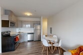 Located in Boston, MA, this well-designed two-bedroom, two-bathroom residence offers a thoughtful single-floor layout that maximizes functionality and comfort. The open-concept living, dining, and kitchen area serves as the heart of the home, featuring hardwood-style flooring that flows seamlessly throughout the main living spaces. The kitchen is outfitted with sleek, modern grey cabinetry, stainless steel appliances including a refrigerator, dishwasher, microwave, and range, as well as light countertops that complement the clean, contemporary aesthetic. A dedicated dining area provides space for a full table setting, while the living area offers ample room for comfortable seating and a natural light source from a large window. Both bedrooms are well-proportioned, with the primary bedroom featuring carpeted flooring, a closet, and a window with outdoor views. The second bedroom also includes a sliding-door closet and hardwood-style flooring. Two full bathrooms each include a shower-tub combination. Additional highlights include three closets, in-unit laundry, a utility room, and convenient hallway connections throughout. The overall ambiance is clean, bright, and modern, well-suited for Boston living.