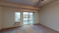 Located at 1559 East Sweet Water Circle in Post Falls, Idaho, this single-floor residence offers a thoughtfully laid-out interior with a blend of practical finishes and comfortable living spaces. The open living area is anchored by plush carpeting and a ceiling fan, with natural light streaming in through large windows and a sliding glass door that leads to a private balcony overlooking the surrounding neighborhood. The transition from entryway to living space is marked by durable wood-look flooring, which continues into the kitchen. The kitchen is efficiently designed with rich dark cabinetry, stone-look countertops, black appliances including a full-size refrigerator and range, and a functional layout that maximizes storage and workspace. Both bedrooms are carpeted and well-lit by exterior-facing windows that bring in ample natural light. The bathrooms feature tile flooring, dark wood vanities with granite-style countertops, and clean white fixtures — one including a full soaking tub and shower combination. A dedicated laundry area accommodates a full-size washer and dryer alongside a water heater, adding everyday convenience. The unit's layout flows naturally between spaces, offering a comfortable and functional living environment in a residential Post Falls community.