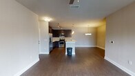 Located at 2701 Old Mayport Rd in Jacksonville, Florida, this single-floor residence offers a thoughtfully designed open-concept layout with modern finishes throughout. The kitchen serves as a central highlight, featuring rich dark espresso cabinetry, stainless steel appliances including a refrigerator, electric range, and microwave, complemented by light quartz countertops and a mosaic tile backsplash. A peninsula with an undermount sink separates the kitchen from the dining and living areas, where pendant lights and a stylish chandelier add refined touches overhead. Dark hardwood-style flooring flows throughout the main living spaces, creating a cohesive and contemporary aesthetic. The dining area is illuminated by an elegant multi-bulb chandelier, providing a welcoming space for gatherings. The bedroom features plush carpeting and a window with natural views, allowing ample natural light to filter in. Two well-appointed bathrooms serve the residence — one offering a soaking tub and shower combination with dark vanity cabinetry and white countertops, and the other featuring a sleek sliding glass walk-in shower enclosure. A dedicated utility area houses a full-size washer and dryer alongside the water heater, adding practical convenience. The overall ambiance is modern, clean, and functional.