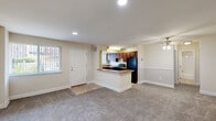 This single-floor unit offers a well-organized layout across a compact but functional footprint. The open-concept living and kitchen area forms the heart of the space, where a carpeted living room with recessed lighting and a ceiling fan connects seamlessly to the kitchen. The kitchen features rich dark wood cabinetry, black appliances including a refrigerator and range, a granite-style countertop, and a peninsula that serves as a natural divider between the cooking and living zones. A window in the living area admits natural light, brightening the neutral beige walls and light carpet throughout.

The bedroom is a comfortable, well-proportioned room with its own window fitted with vertical blinds, soft carpet underfoot, and a double-door closet providing ample storage. The room's neutral tones and clean lines create a calm, restful atmosphere.

The bathroom is straightforward and functional, featuring a full tub and shower combination with white subway-style tile surround, a toilet, and a clean, minimal design. Tile flooring in the entry area transitions to carpet in the main living and sleeping spaces, adding subtle variation to the overall aesthetic. The unit maintains a consistent, understated palette throughout.
