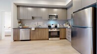 Located at 1110 Lawson Avenue in Kelowna, BC, this thoughtfully designed 1-bedroom, 3-bathroom unit offers a functional and stylish single-floor layout. Light hardwood flooring flows throughout, complementing a bright, neutral palette that enhances the sense of openness.

The kitchen is a functional centerpiece, outfitted with stainless steel appliances including a refrigerator, range, microwave, and dishwasher, alongside two-tone cabinetry in warm wood and matte grey, dark countertops, and a tiled backsplash. A dining area adjacent to the kitchen provides a natural gathering space.

The living room is filled with natural light through a large picture window overlooking an outdoor balcony, creating an airy, welcoming atmosphere. The bedroom features the same large-format windows with outdoor views, maintaining the bright character of the home. A dedicated walk-in closet with open shelving and wicker storage provides well-organized storage.

A dedicated office space offers a quiet area for work or study. Three bathrooms serve the unit, including one with a full soaker tub and shower combination. The in-unit laundry room includes a stacked washer and dryer alongside a water heater, keeping all essentials conveniently on-site.