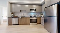 Located at 1110 Lawson Avenue in Kelowna, BC, this thoughtfully designed 1-bedroom, 3-bathroom unit offers a functional and stylish single-floor layout. Light hardwood flooring flows throughout, complementing a bright, neutral palette that enhances the sense of openness.

The kitchen is a functional centerpiece, outfitted with stainless steel appliances including a refrigerator, range, microwave, and dishwasher, alongside two-tone cabinetry in warm wood and matte grey, dark countertops, and a tiled backsplash. A dining area adjacent to the kitchen provides a natural gathering space.

The living room is filled with natural light through a large picture window overlooking an outdoor balcony, creating an airy, welcoming atmosphere. The bedroom features the same large-format windows with outdoor views, maintaining the bright character of the home. A dedicated walk-in closet with open shelving and wicker storage provides well-organized storage.

A dedicated office space offers a quiet area for work or study. Three bathrooms serve the unit, including one with a full soaker tub and shower combination. The in-unit laundry room includes a stacked washer and dryer alongside a water heater, keeping all essentials conveniently on-site.