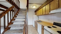 Located at 3444 Tivoli Ct in Columbus, Ohio, this two-story residence offers a straightforward and functional layout distributed across two floors connected by a carpeted staircase with classic wood railings and balusters. The kitchen is positioned conveniently on the main level adjacent to the staircase and is equipped with warm oak-toned cabinetry, laminate countertops, a double-basin sink, a dishwasher, a range, and a full-size refrigerator. Tile-style flooring runs throughout the kitchen, providing a practical and easy-to-maintain surface. The upper level features open, carpeted rooms that offer a comfortable and quiet atmosphere. Ceiling fans are present in the upper-floor rooms, providing ventilation and light. A window allows natural light to filter in, offering views of the surrounding neighborhood. The textured ceilings are consistent throughout the space, adding a subtle visual detail. The bathroom includes a full tub and shower combo with white tile surround and chrome fixtures, maintaining a clean and classic aesthetic. Overall, the space presents a practical, no-frills layout well-suited for everyday living, with functional finishes and a clear two-level floor plan.