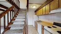 Located at 3444 Tivoli Ct in Columbus, Ohio, this two-story residence offers a straightforward and functional layout distributed across two floors connected by a carpeted staircase with classic wood railings and balusters. The kitchen is positioned conveniently on the main level adjacent to the staircase and is equipped with warm oak-toned cabinetry, laminate countertops, a double-basin sink, a dishwasher, a range, and a full-size refrigerator. Tile-style flooring runs throughout the kitchen, providing a practical and easy-to-maintain surface. The upper level features open, carpeted rooms that offer a comfortable and quiet atmosphere. Ceiling fans are present in the upper-floor rooms, providing ventilation and light. A window allows natural light to filter in, offering views of the surrounding neighborhood. The textured ceilings are consistent throughout the space, adding a subtle visual detail. The bathroom includes a full tub and shower combo with white tile surround and chrome fixtures, maintaining a clean and classic aesthetic. Overall, the space presents a practical, no-frills layout well-suited for everyday living, with functional finishes and a clear two-level floor plan.