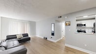 Located at 2220 Devonport Dr in Lexington, Kentucky, this single-floor, 2-bedroom, 2-bathroom home offers a practical and cohesive layout unified by light wood-tone flooring and neutral gray walls throughout. The spacious living room is the heart of the home, featuring a textured ceiling, recessed lighting, and a large window with vertical blinds that allows natural light to fill the open area. A secondary living or flex space connects to the main living area, providing additional room for relaxation or entertainment. The two bedrooms are comfortably sized, each featuring windows with blinds that bring in natural light, textured ceilings, and ample floor space. The generously sized primary bedroom includes a closet and direct access to the hallway. Both bathrooms are functional and straightforward, with one featuring a shower-tub combination. Two hallways connect the living spaces to the bedrooms and bathrooms, ensuring a logical flow throughout the home. The kitchen, visible from the main corridor, features light cabinetry and a practical layout. Clean white trim and six-panel interior doors with matte black hardware are consistent throughout, contributing to the home's cohesive, modern-neutral aesthetic.