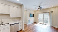 Located at 2100 Corona Rd in Columbia, MO, this two-bedroom, one-bathroom unit offers a well-designed layout across a single floor. Warm hardwood-style flooring runs consistently throughout the living areas and bedrooms, lending a cohesive and inviting feel to the entire space.

The kitchen is a standout feature, equipped with stainless steel appliances including a refrigerator, electric range, over-the-range microwave, and dishwasher. Crisp white shaker-style cabinetry extends to the ceiling, providing generous storage, while light countertops and recessed lighting complete the functional, modern aesthetic.

Both bedrooms are finished with the same hardwood-style flooring and neutral wall tones. Ceiling fans are installed in each room, and windows fitted with horizontal blinds allow for natural light and outdoor views. The primary bedroom includes a double-door closet, offering practical storage.

The bathroom features tile flooring, a single vanity with cabinetry, and a full tub-shower combination. A dedicated laundry room accommodates a full-size washer and dryer side by side, with additional shelving and a window that brings in natural light. A hallway connects all rooms efficiently, rounding out this clean and practical residential unit.