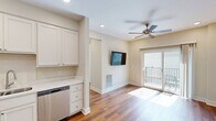 Located at 2100 Corona Rd in Columbia, MO, this two-bedroom, one-bathroom unit offers a well-designed layout across a single floor. Warm hardwood-style flooring runs consistently throughout the living areas and bedrooms, lending a cohesive and inviting feel to the entire space.

The kitchen is a standout feature, equipped with stainless steel appliances including a refrigerator, electric range, over-the-range microwave, and dishwasher. Crisp white shaker-style cabinetry extends to the ceiling, providing generous storage, while light countertops and recessed lighting complete the functional, modern aesthetic.

Both bedrooms are finished with the same hardwood-style flooring and neutral wall tones. Ceiling fans are installed in each room, and windows fitted with horizontal blinds allow for natural light and outdoor views. The primary bedroom includes a double-door closet, offering practical storage.

The bathroom features tile flooring, a single vanity with cabinetry, and a full tub-shower combination. A dedicated laundry room accommodates a full-size washer and dryer side by side, with additional shelving and a window that brings in natural light. A hallway connects all rooms efficiently, rounding out this clean and practical residential unit.