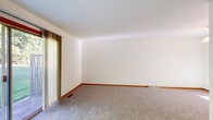 Located at 1359 Dewberry Pl NE in Grand Rapids, Michigan, this three-floor home offers a straightforward, functional layout with well-defined living spaces spread across its levels. The main floor features a kitchen equipped with white cabinetry, granite-style countertops, light wood-look flooring, and white appliances including a range, dishwasher, and refrigerator. A peninsula counter provides additional workspace and a natural transition into the adjacent living areas. The living room is generously sized, finished with neutral carpet, warm wood baseboard trim, and a sliding glass door that opens to a deck and backyard, bringing in natural light and outdoor views of mature trees and green lawn. Multiple carpeted rooms on the upper level are bright and clean with neutral walls, wood-trimmed doors, and consistent baseboard detailing, offering flexible use as bedrooms or additional living spaces. The staircase connects all three levels, including access to the unfinished basement, which presents a wide-open footprint with painted concrete block walls, exposed wood joist ceiling, small egress windows, a utility sink, and a painted staircase — offering significant potential for future finishing or use as storage and utility space.