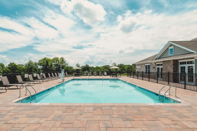 Disfrute de la relajación en la piscina climatizada al aire libre, perfecta para tomar el sol o disfrutar de un refrescante baño. - Meadow Ridge Luxury Apartments