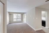 Located at 3904 Greencastle Ridge Dr in Burtonsville, Maryland, this 2-bedroom, 1-bathroom residence offers a well-designed single-floor layout. The open living area is highlighted by large windows with balcony access, filling the space with natural light and views of surrounding trees. Warm neutral tones and plush carpeting throughout the living and bedroom areas create a comfortable, cohesive ambiance.

The kitchen is thoughtfully appointed with contemporary flat-front cabinetry in a warm taupe finish, light granite-style countertops, a white subway tile backsplash, black appliances, and wood-look flooring. It opens toward a windowed dining area, enhancing its functional flow.

The spacious primary bedroom offers generous proportions and a window with outdoor views, while the second bedroom is equally well-lit with its own window. Both rooms feature soft carpeting and neutral wall tones.

The full bathroom is fitted with an extended granite-style vanity countertop, a large framed mirror, modern fixtures, and a shower/tub combination. A connecting hallway with wood-look flooring links the bathroom to the bedrooms, providing a practical and organized circulation path throughout the residence.