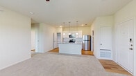 This single-floor residence offers a thoughtfully designed layout across a comfortable footprint, accommodating two bedrooms and two bathrooms. The open-concept living and kitchen area serves as the heart of the unit, featuring light-toned carpet in the living space that transitions to hardwood-style flooring in the kitchen. The kitchen is equipped with stainless steel appliances, including a refrigerator, range, and over-the-range microwave. White cabinetry with a subway tile backsplash lines the walls, while a central island with a grey countertop and undermount sink provides additional prep space and seating. Pendant lighting above the island adds a modern accent.

The primary bedroom features elevated ceilings, a ceiling fan, and access to a walk-in closet outfitted with wire shelving. The second bedroom benefits from a large window that brings in natural light. Both bathrooms are finished cleanly, with one featuring a tub-shower combination with white subway tile surround and hardwood-style flooring. A dedicated laundry area with washer and dryer hookups adds everyday convenience. Throughout, neutral tones and clean finishes give the space a bright, move-in-ready character.