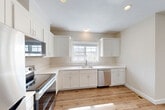 Located at 5 Eagle Brook Blvd in Wrentham, MA, this three-floor townhouse offers 2 bedrooms and 3 bathrooms thoughtfully distributed across well-proportioned living spaces. The entry-level garage and finished lower level — featuring recessed lighting and warm wood-look luxury vinyl plank flooring — provide flexible space ideal for a recreation room, home office, or additional living area. The main floor serves as the heart of the home, where an open-concept layout connects the kitchen, dining room, and living room. The kitchen is outfitted with white shaker cabinetry, stainless steel appliances including a refrigerator, range, and over-the-range microwave, all set atop the same light hardwood-style flooring that flows throughout. A deck off the main level extends the living space outdoors, offering views of the surrounding treeline and open sky. The upper floor hosts both bedrooms, including a generously sized primary bedroom, each carpeted for comfort and featuring windows that bring in natural light. The bedrooms are complemented by closet space and well-appointed bathrooms with clean, neutral finishes. The home's consistent palette of warm neutrals and crisp white trim creates a cohesive, move-in-ready aesthetic throughout.