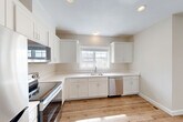 Located at 5 Eagle Brook Blvd in Wrentham, MA, this three-floor townhouse offers 2 bedrooms and 3 bathrooms thoughtfully distributed across well-proportioned living spaces. The entry-level garage and finished lower level — featuring recessed lighting and warm wood-look luxury vinyl plank flooring — provide flexible space ideal for a recreation room, home office, or additional living area. The main floor serves as the heart of the home, where an open-concept layout connects the kitchen, dining room, and living room. The kitchen is outfitted with white shaker cabinetry, stainless steel appliances including a refrigerator, range, and over-the-range microwave, all set atop the same light hardwood-style flooring that flows throughout. A deck off the main level extends the living space outdoors, offering views of the surrounding treeline and open sky. The upper floor hosts both bedrooms, including a generously sized primary bedroom, each carpeted for comfort and featuring windows that bring in natural light. The bedrooms are complemented by closet space and well-appointed bathrooms with clean, neutral finishes. The home's consistent palette of warm neutrals and crisp white trim creates a cohesive, move-in-ready aesthetic throughout.