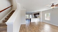 This well-appointed two-story home in Chattanooga, Tennessee offers three bedrooms and three bathrooms across two thoughtfully designed floors. The main level welcomes you through a Craftsman-style front door into a bright entry foyer accented with crown molding and hardwood-style flooring that flows seamlessly throughout. The open-concept layout connects the living room—featuring a ceiling fan and natural light from multiple windows—to the kitchen, making the space ideal for everyday living and entertaining. The kitchen is a standout, outfitted with rich dark cabinetry, granite-look countertops, a peninsula breakfast bar with pendant lighting, and stainless steel appliances including a gas range, microwave, and French door refrigerator. Crown molding adds a refined touch throughout the main level. Upstairs, the primary bedroom offers a generous footprint with plush carpeting, a ceiling fan, and natural light. Two additional bedrooms, also carpeted with ceiling fans, provide comfortable secondary accommodations. Three full bathrooms serve the home, including one featuring a tub-shower combination with chrome fixtures. Four closets provide ample storage throughout. The home's clean, neutral color palette and consistent finishes create a cohesive and move-in ready atmosphere.