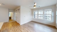 This well-appointed one-bedroom unit at 1803 S 46th Street in Rogers, Arkansas offers a thoughtfully designed single-floor layout with a clean, contemporary aesthetic throughout. The open-concept kitchen serves as the heart of the home, showcasing a striking two-tone design with crisp white upper cabinetry and slate-gray lower cabinets, complemented by a white subway tile backsplash and light quartz countertops. A central island with a built-in sink provides additional prep space and casual seating, while stainless steel appliances — including a French door refrigerator, electric range, and microwave — complete the modern look. Pendant lighting overhead and recessed ceiling lights add warmth and style. The kitchen flows naturally into the living area, which features light hardwood-style flooring, large windows with roller shades, and a ceiling fan, inviting an abundance of natural light and outdoor views. The generously sized bedroom is finished with plush carpet, a ceiling fan with light fixture, and large windows that continue the bright, airy feel of the space. A connected bathroom with dark cabinetry is accessible directly from the bedroom. The walk-in closet is outfitted with wrap-around wire shelving and hanging rods on multiple levels, offering ample storage. Neutral tones and modern finishes create a cohesive and inviting ambiance throughout.