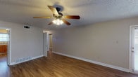 This single-story, 2-bedroom, 1-bathroom home delivers a well-organized and functional layout across a comfortable footprint. The living area features warm hardwood-style flooring, neutral-toned walls, and a ceiling fan with light fixture overhead, while a textured ceiling adds classic character throughout the space. Natural light flows in through windows fitted with blinds, creating a bright and welcoming atmosphere.

The kitchen is equipped with warm oak cabinetry, granite-look countertops, and a stainless steel gas range with an overhead ventilation hood, offering ample storage and prep space for everyday cooking.

Both bedrooms are carpeted for comfort and include ceiling fans, windows for natural light, and generous closet space with built-in rods and shelving. The full bathroom features a single-sink vanity with oak cabinetry, a wall-mounted mirror, and a shower-tub combination.

A dedicated utility area provides washer and dryer hookups, built-in shelving, and an electrical panel, adding practicality to the home. Hardwood-style flooring runs throughout the main living areas, tying the space together with a cohesive and clean aesthetic. This home is a straightforward and well-appointed residence suited for everyday living.