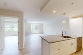 Located at 175 James in Worcester, MA, this well-appointed one-bedroom, one-bathroom unit offers a thoughtfully designed single-floor layout with a clean, modern aesthetic. Light wood-style flooring runs throughout the entire space, complemented by neutral warm-white walls that create a bright and cohesive atmosphere.

The open-concept kitchen and living area serves as the heart of the unit. The kitchen is outfitted with crisp white shaker-style cabinetry, speckled granite countertops, a brass-toned undermount sink, and a full suite of stainless steel appliances including a refrigerator, electric range, and microwave. A peninsula with pendant lighting provides additional counter space and separates the kitchen from the open living area, which is bathed in natural light from multiple windows.

The spacious primary bedroom features a wall-mounted mini-split HVAC system, a double-door closet, and a window with views of the surrounding greenery. An additional room offers flexible use as a living or secondary space, also with natural light and a mini-split unit.

The full bathroom is finished with matching granite countertops, white cabinetry, brushed nickel fixtures, and a tub-shower combination. In-unit laundry is conveniently stacked within the bathroom. Every detail reflects a fresh, modern finish throughout this well-planned Worcester residence.