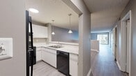 Located at 2600 Colonial Towers Dr in Memphis, TN, this single-floor, 2-bedroom, 1-bathroom residence offers a well-organized layout with a blend of practical design and updated finishes throughout. The kitchen is a standout feature, boasting white cabinetry, light stone-look countertops, wood-look vinyl flooring, and black appliances including a refrigerator, range, and dishwasher. Pendant lighting adds a modern touch, and a half-wall peninsula opens the kitchen seamlessly to the adjacent dining and living areas, creating a connected and functional flow. The living area features wood-look vinyl flooring, neutral gray walls, and a sliding glass door that invites natural light and provides access to outdoor views. The generously sized primary bedroom is carpeted and offers ample square footage for comfortable furnishing. The second bedroom, also carpeted with neutral tones, provides a quiet and versatile space. A hallway connects the bedrooms to the full bathroom, which includes a tub-shower combination with white tile surround and grab bar fixtures. Textured ceilings are consistent throughout, and clean white baseboards complement the neutral color palette, giving the entire residence a fresh, move-in-ready appearance.