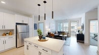 This well-appointed 2-bedroom, 2-bathroom residence at 19 Harnett St in Wilmington, NC offers a thoughtfully designed single-floor layout that maximizes both comfort and functionality. The open-concept living area seamlessly connects the kitchen, dining, and living spaces, all bathed in natural light from large windows with sleek horizontal blinds.

The kitchen is a standout feature, showcasing crisp white shaker cabinetry with matte black hardware, a generous quartz-topped island with bar seating, stainless steel appliances, a tile backsplash, and dramatic pendant lighting overhead. Light wood-style flooring flows throughout the main living areas, enhancing the bright, airy atmosphere.

The living room is spacious and inviting, with abundant natural light and direct access to a private balcony. Both bedrooms are carpeted and well-lit, each offering dedicated closet space and ceiling fans for year-round comfort.

The two bathrooms are finished in a clean, modern palette featuring light wood flooring, white cabinetry with matte black fixtures, and recessed lighting. One bathroom includes a soaking tub and double vanity, while the other features a walk-in glass shower. Additional conveniences include in-unit laundry and two closets, rounding out this polished Wilmington residence.