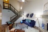 This two-story residence in Atlanta, GA features 2 bedrooms and 2.5 bathrooms across a well-appointed floor plan. The main level opens to a welcoming entryway with rich hardwood-style flooring that flows throughout. The living room impresses with soaring vaulted ceilings, a ceiling fan, and a contemporary staircase with cable-rail detailing, creating an open and airy atmosphere. Natural light pours in through multiple windows fitted with elegant drapery. The dining area accommodates a full dining set beneath a stylish pendant light, with views to the outdoors. The galley-style kitchen is outfitted with granite countertops, gray shaker cabinetry, a dark tile backsplash, and a full suite of stainless steel appliances. A half bathroom on the main level features granite vanity counters and a large framed mirror. Upstairs, both bedrooms offer plush carpeting and vaulted ceilings. The primary bedroom is generously sized with ample natural light, while the second bedroom provides a cozy and comfortable retreat. Each full bathroom is finished with granite countertops and modern fixtures. The two-story layout, quality finishes, and thoughtful design details make this Atlanta home a well-rounded and functional living space.