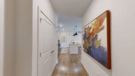 Located at 157 Talley Crossing in Athens, GA, this single-story 2-bedroom, 2-bathroom home offers a clean, modern aesthetic with warm, inviting interiors. A welcoming hallway adorned with wide-plank wood-look flooring leads into the open-concept kitchen and living area. The kitchen is a functional centerpiece, featuring gray cabinetry, granite countertops, stainless steel appliances, a white kitchen island with bar seating, and a pair of sleek black pendant lights overhead. The adjoining living room is bright and airy, benefiting from natural light through large windows and offering comfortable, versatile space for everyday living. The primary bedroom is generously sized, complete with plush carpet, a ceiling fan, and natural light, accompanied by a walk-in closet with built-in shelving and hanging rods for ample storage. The second bedroom offers similar comfort and accessibility. Both bathrooms are finished with granite countertops, gray vanity cabinetry, and wood-look flooring. A dedicated laundry area and a connecting hallway round out the thoughtful floor plan. Neutral tones, recessed lighting, and consistent finishes throughout create a cohesive and polished living environment.