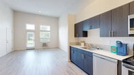 This 2-bedroom, 2-bathroom residence features a thoughtfully designed single-level layout that maximizes functionality and comfort. The open-concept living area is anchored by light wood-look flooring and soaring ceilings that enhance the sense of space, with large windows and a glass-panel entry door flooding the room with natural light and offering pleasant views of surrounding greenery.

The kitchen is well-appointed with dark wood cabinetry, a subway tile backsplash, light countertops, and a full suite of stainless steel appliances including a range, over-the-range microwave, refrigerator, and dishwasher — providing an efficient and stylish cooking space that flows seamlessly into the living area.

Both bedrooms feature plush wall-to-wall carpeting, generous closet storage, and windows that bring in natural light. The primary bedroom offers a comfortable, private retreat with ample room for furnishings. Each of the two bathrooms is finished with wood-toned vanities, tile backsplash accents, a sink with a large mirror, and a full shower-tub combination, all set on light wood-look flooring that maintains a clean, cohesive aesthetic throughout the residence.