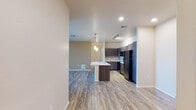This single-floor residence presents a thoughtfully designed open-concept layout that connects the entryway, kitchen, and living areas seamlessly. Wood-look plank flooring runs throughout the main living spaces, creating a cohesive and contemporary aesthetic, while soft carpeting adds warmth to the bedrooms.

The kitchen serves as the focal point of the living area, featuring dark espresso-toned cabinetry paired with light countertops and a subway tile backsplash. A generously sized island with an integrated sink provides additional workspace and casual dining potential, illuminated by pendant lights and a track lighting system overhead. Black appliances, including a full-size refrigerator, range, microwave, and dishwasher, complete the modern kitchen suite.

The living area offers comfortable proportions, natural light from large windows with blinds, and a ceiling fan for added comfort. The bedrooms are carpeted and similarly benefit from natural light and ceiling fans.

Two full bathrooms are finished consistently with dark vanity cabinetry, white countertops, and wood-look flooring. One bathroom includes a soaking tub and shower combination, while the other features a walk-in shower, both with well-lit vanity mirrors.