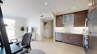 This thoughtfully designed single-floor residence offers three bedrooms and two bathrooms within a well-organized, efficient layout. The open-concept living and kitchen area forms the heart of the home, featuring light wood-tone flooring, recessed lighting, and clean white walls that create a bright, airy atmosphere throughout. The kitchen is outfitted with rich wood-grain cabinetry accented by frosted glass upper panels, a full suite of stainless steel appliances including a dishwasher, range, microwave, and refrigerator, and a sleek white countertop with an undermount sink. The living room receives generous natural light through large floor-to-ceiling sliding glass doors that open directly onto a private balcony with outdoor views. The bedrooms are calm and well-lit, with the secondary bedrooms featuring natural light from dedicated windows. The primary bedroom offers a comfortable, serene retreat. Closet storage is provided with adjustable wire shelving systems. The bathrooms are finished with large-format tile flooring, wood-toned vanity cabinetry, undermount sinks, and full-width mirrors. A hallway connects the private quarters, ensuring a functional and cohesive flow throughout the entire residence.