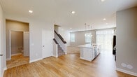 This two-story home on 4th St N in Lake Elmo, Minnesota offers a thoughtfully designed layout with modern finishes throughout. The main floor showcases an open-concept living and kitchen area united by light hardwood flooring and a neutral color palette. The kitchen is a standout feature, equipped with white shaker-style cabinetry, light quartz countertops, a large center island with a built-in sink and pendant lighting overhead, and a full suite of stainless steel appliances including a gas range, microwave, refrigerator, and dishwasher. A subway tile backsplash and recessed lighting add polish to the space. Large windows and vertical blinds allow ample natural light to fill the open living area, which flows seamlessly from the kitchen. A staircase with a dark wood handrail connects the main level to the upper floor. Bathrooms feature tile flooring and clean, simple fixtures. The upper level includes carpeted bedrooms with windows offering outdoor views, as well as a generously sized walk-in closet with wire shelving and a dedicated laundry room with a full-size washer and dryer. The overall aesthetic is clean, modern, and move-in ready.