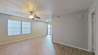 This single-story, 2-bedroom, 2-bathroom unit offers a functional and well-organized layout across a compact but efficiently utilized floor plan. The living room serves as the central gathering space, featuring light wood-look plank flooring, a textured ceiling, a ceiling fan with integrated lighting, and a sliding glass door fitted with vertical blinds that allows natural light to filter in. A side window with horizontal blinds further brightens the area.

The galley-style kitchen is thoughtfully designed with gray cabinetry, light quartz-style countertops, a tile mosaic backsplash, and black appliances including a refrigerator, electric range, and dishwasher. The layout maximizes storage and counter efficiency within the space.

Both bedrooms feature wood-look flooring, neutral gray walls, and windows with blinds that provide natural light. The primary bedroom includes a dedicated walk-in closet with built-in shelving and hanging rods. The second bedroom is equipped with a ceiling fan and its own closet.

Each bathroom includes a tub-shower combination, toilet, and a vanity with gray cabinetry and a light countertop surface. The consistent neutral color palette and wood-look flooring throughout give the unit a cohesive, clean aesthetic.