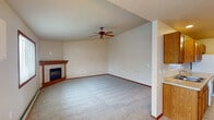 This single-floor residence offers a thoughtfully designed layout with a variety of functional and comfortable living spaces. The main living area immediately impresses with soaring vaulted ceilings and a ceiling fan overhead, while a tile-surround fireplace with a wood mantel serves as a natural focal point. Plush carpeting and warm wood baseboards run throughout, lending a cohesive and inviting feel to the space.

Adjacent to the living room, a dining area benefits from natural light streaming through a large sliding glass door, accompanied by a decorative pendant light fixture. A pass-through window connects this space to the kitchen, which is equipped with warm oak cabinetry, ample counter space, tile flooring, and white appliances including a range, over-the-range microwave, and refrigerator.

The bedrooms are generously proportioned, each featuring plush carpeting, baseboard heating, and windows that bring in natural light. One bedroom includes dual closets, providing excellent storage capacity. The primary bathroom is elongated and well-equipped, featuring tile flooring, a vanity with extended countertop, a toilet, and a glass-enclosed walk-in shower. A second bathroom offers a tub and toilet, accessible from the bedroom hallway. Throughout the space, warm oak wood doors and trim provide a consistent, classic finish.