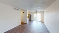Located in Windswept Cove, Austin, TX, this one-bedroom, one-bathroom unit offers a well-organized single-floor layout designed for comfortable everyday living. Warm hardwood-style flooring runs throughout the main living areas and bedroom, providing a cohesive and inviting aesthetic. The open-concept living room is generously proportioned, featuring a textured ceiling, a ceiling fan, and a sliding glass door fitted with vertical blinds that opens to a private balcony — allowing natural light to pour in and offering pleasant outdoor views. The galley-style kitchen is efficiently arranged with white cabinetry, brown laminate countertops, a stainless steel dishwasher, and a full-size refrigerator, providing ample storage and counter space for meal preparation. The bedroom is a comfortable size, also featuring hardwood-style floors, a ceiling fan, and direct access to the hallway leading to the bathroom. The bathroom is clean and functional, equipped with a full bathtub and shower combo with white tile surround. A dedicated closet and hallway complete the layout, adding practical storage. The overall ambiance is bright, neutral, and move-in ready, suited for those seeking a functional home in south Austin.