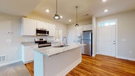Located at 6650 Liberty Grand Blvd. in Powell, Ohio, this well-appointed two-story home offers a thoughtfully designed layout across two levels. The main floor showcases an open-concept design where the kitchen flows seamlessly into the living area, creating an inviting and functional space for everyday living and entertaining. The kitchen is a standout feature, equipped with white shaker-style cabinetry, granite countertops, and a large center island with an undermount sink. Stainless steel appliances, including a range, built-in microwave, and refrigerator, complement the space, while stylish pendant lighting adds a contemporary touch. Rich hardwood flooring extends throughout the main living areas, transitioning to plush carpet in the living room and upper level. A half bath with hardwood flooring is conveniently located on the main floor. Upstairs, the home includes carpeted bedrooms bathed in natural light from generously sized windows. The primary bedroom features vaulted ceilings and a spacious walk-in closet outfitted with wire shelving and storage racks. A dedicated laundry area with a full-size washer and dryer rounds out the upper level, adding practical convenience to the home's overall design.