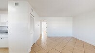 Located in Deerfield Beach, Florida, this single-floor, 2-bedroom, 1-bathroom residence offers a clean and functional layout finished consistently with light beige ceramic tile flooring throughout. The combined kitchen and living area forms the heart of the home, with the kitchen featuring white cabinetry, dark granite-style countertops, stainless steel appliances including a refrigerator and range, and louvered closet doors providing additional storage. The open living room area is bright and airy, with white walls and a textured ceiling. Both bedrooms are well-proportioned, each with windows that allow natural light to fill the rooms, white walls, and tile flooring. The primary bedroom includes a full-width louvered bifold closet, providing generous storage space. The single bathroom is finished with beige tile surround walls, a soaking tub with shower, and black matte fixtures that add a modern contrast. A dedicated hallway connects the rooms efficiently. The overall aesthetic is clean, minimal, and move-in ready, making it a practical and comfortable home in the heart of South Florida.
