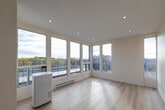 Located at 1704 Victoria Park Ave in Toronto's east end, this thoughtfully designed unit offers a compact yet functional single-floor layout comprising a living room, kitchen, bathroom, hallway, and a private balcony. Light hardwood flooring flows throughout the main living areas, lending a warm, cohesive aesthetic. The bright living room is anchored by a large bank of floor-to-ceiling windows that flood the space with natural light and frame expansive views of the surrounding neighbourhood and skyline. Recessed pot lighting complements the natural brightness throughout. The contemporary kitchen features two-toned cabinetry — warm wood uppers paired with slate-grey lowers — white quartz countertops, a vertical subway tile backsplash, stainless steel appliances, and a built-in microwave range hood. The bathroom is finished with full beige tile surround, a soaker tub with overhead shower, and a small window for ventilation. The private balcony, accessible from the living area, offers generous open-air space with a metal railing, partial overhead coverage, and sweeping views of the Toronto skyline, autumn tree canopy, and surrounding rooftops — an ideal outdoor retreat above the city.