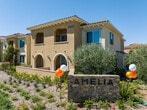 Located at Village at the Park in Camarillo, California, this single-story residence offers a thoughtfully designed open-concept layout that seamlessly connects the kitchen, dining, and living areas. Wood-style flooring runs throughout the main living spaces, complementing the bright, neutral color palette that defines the interior aesthetic.

The kitchen is well-equipped with stainless steel appliances, including a refrigerator, range, microwave, and dishwasher. Grey shaker-style cabinetry pairs with white subway tile backsplash and light countertops, creating a clean, modern workspace. A dining area adjacent to the kitchen provides convenient everyday functionality.

The living room benefits from large windows that invite abundant natural light and offer views of the surrounding community. A ceiling fan adds comfort to the space, while recessed lighting enhances the bright, airy atmosphere.

The bedroom features plush carpeting, a vaulted ceiling detail, and a walk-in closet with built-in shelving, providing generous storage. A window allows natural light to filter in, keeping the room feeling open and comfortable.

The bathroom includes grey cabinetry, a wide vanity with a single sink, a large mirror, wood-style flooring, and a shower-tub combination. The overall ambiance of the unit is modern, functional, and well-lit.