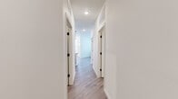 This single-story home presents a cohesive, modern design carried consistently throughout its spaces. The hallways are bright and well-organized, featuring light hardwood-style flooring, crisp white walls, and interior doors accented with black hardware — a detail that lends a contemporary touch to the overall aesthetic.

The kitchen serves as a standout feature, showcasing rich dark espresso cabinetry that extends to the ceiling for ample storage, complemented by granite countertops with warm gold and cream tones. A peninsula with an undermount sink provides additional workspace and casual seating. Stainless steel appliances, including a refrigerator, range, and microwave, complete the well-appointed cooking space. Pendant lighting adds a polished finishing touch.

A dedicated laundry room includes a full-size washer and dryer, a utility shelf, and water heater storage, keeping household functions neatly organized. The bathroom features a tub-shower combination with tile surround, a dark-framed vanity mirror, granite-topped vanity, and matching black fixtures.

The attached garage is generously sized with a concrete floor, overhead lighting, and an automatic door opener. An additional unfinished corridor provides extended utility or storage space. Throughout, the home maintains a clean, functional character.