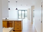 This 710 sq ft one-bedroom, one-bathroom unit at 2310 Richmond Street in London, Ontario, offers a thoughtfully designed modern living space on a single floor. The open-concept kitchen and living area serves as the heart of the unit, featuring light hardwood flooring throughout. The contemporary kitchen is equipped with stainless steel appliances — including a range, microwave, and refrigerator — complemented by a two-tone cabinet design blending white uppers with warm wood-toned lowers. A quartz-topped island with an undermount sink and stylish pendant lighting adds both function and visual appeal. The living area is bright and airy, with large floor-to-ceiling sliding glass doors providing balcony access and sweeping outdoor views of the surrounding neighbourhood. The 110 sq ft bedroom includes a calming blue accent wall and light hardwood floors. Two closets, including a walk-in with wire shelving, offer generous storage. The bathroom features large-format light tile flooring and a tub-shower combination adorned with striking dark subway tile. Neutral tones and recessed lighting throughout create a clean, contemporary ambiance.