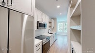 Located in Morrisville, NC, this thoughtfully designed 1-bedroom, 1-bathroom unit offers a clean, modern aesthetic throughout its efficient single-floor layout. The galley-style kitchen is a standout feature, outfitted with white shaker cabinets, quartz countertops, a white subway tile backsplash, stainless steel appliances including a range, microwave, dishwasher, and refrigerator, along with open wood floating shelves and a deep single-basin sink with a matte black faucet. Light wood-tone flooring runs throughout, creating a warm and cohesive feel. The spacious primary bedroom is generously proportioned and filled with natural light through multiple windows dressed with white horizontal blinds, offering views of the surrounding greenery. A ceiling fan adds both function and comfort to the room. The bathroom features a white vanity with an undermount sink, a framed mirror, and a walk-in shower, maintaining the clean, contemporary style found throughout the unit. Additional spaces include a dedicated closet and an entrance area, providing practical everyday functionality. Recessed lighting and neutral wall tones contribute to a bright, airy ambiance, making this a well-appointed and inviting space in the heart of Morrisville.