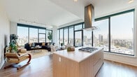 Located in the heart of downtown San Diego, this sophisticated high-rise residence at 310 A St offers sweeping panoramic views of the city skyline through expansive floor-to-ceiling windows that flood the interior with natural light. The open-concept living and dining area is anchored by wide-plank hardwood flooring and seamlessly connects to a chef's kitchen outfitted with a large center island, gas cooktop, integrated range hood, stainless steel appliances, light wood cabinetry, and quartz countertops. A dedicated wet bar with a wine refrigerator and glass shelving adds an elegant entertaining touch. The living area features generous proportions with unobstructed city views on multiple sides, creating a bright and airy ambiance throughout. The bedrooms are tranquil retreats, each benefiting from large windows with striking downtown vistas. The primary suite includes a spacious walk-in closet with custom built-in shelving and a well-appointed bathroom finished in marble-style tile, complete with a soaking tub and separate vanity. Additional closet space with thoughtful organization systems provides ample storage. Clean white walls, recessed lighting, and a consistent use of natural wood tones throughout contribute to a cohesive, contemporary aesthetic.