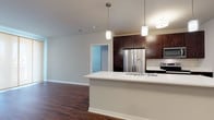 Located at 8370 S Orchard Way in Oak Creek, Wisconsin, this single-floor residence offers a thoughtfully designed open-concept layout that seamlessly connects the kitchen, dining, and living areas. The kitchen is a standout feature, equipped with rich dark-toned cabinetry, stainless steel appliances including a refrigerator, microwave, and range, and a large peninsula with a white countertop and undermount sink. Stylish pendant lighting above the peninsula adds a modern touch, while durable hardwood-style flooring flows throughout the main living areas.

The living space is bright and open, benefiting from large sliding glass doors fitted with roller shades that invite natural light. The bedroom areas feature plush carpeting, ample closet space with double doors, and windows with blinds. One bathroom is appointed with a full soaking tub and tiled surround, while another features a glass-enclosed shower, dark cabinetry, white countertops, and hardwood-style flooring for a sleek, contemporary look. Throughout the residence, neutral wall tones and clean white trim create a cohesive, modern aesthetic that is both inviting and functional.