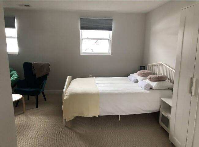 Queen size bed, window, seating area. - 7922 Fitzroy St